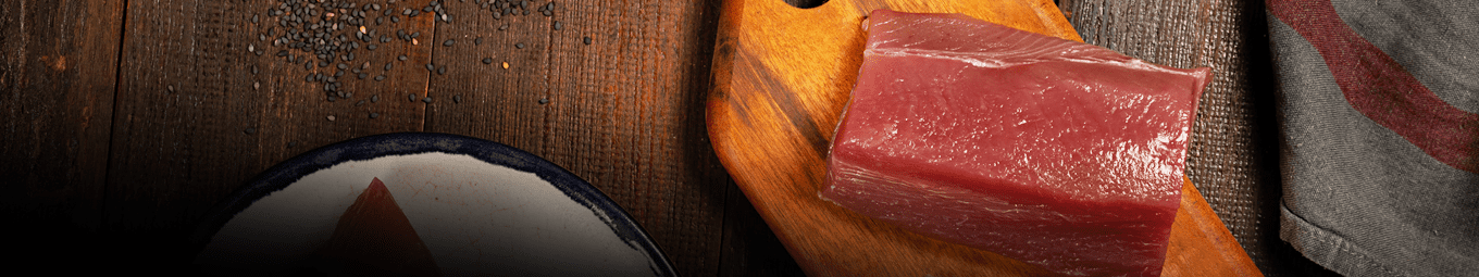 Foto de cubos e lombo de atum servidos em tábua de madeira e prato de cerâmica