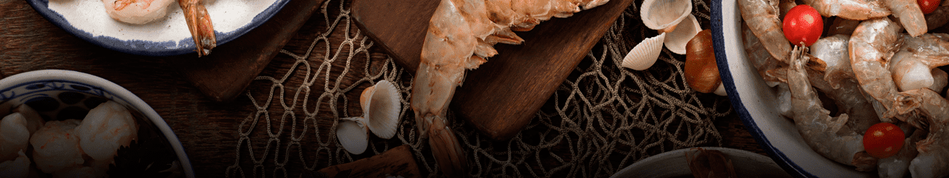 Fotos de camarões inteiros, mescladas com conchas, rede de pesca e tomates. Dispostas em um fundo escuro.